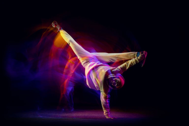A man breakdancing, standing on his hand with legs spread above his head.