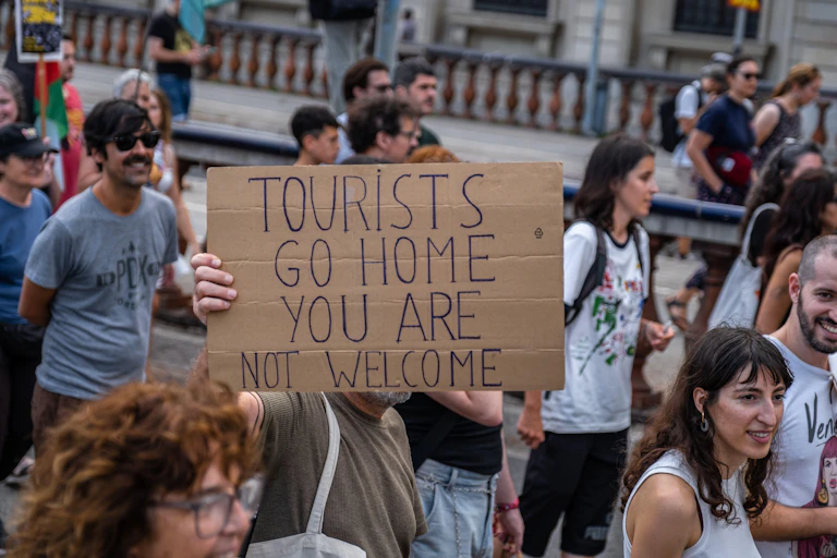 protester in Barcelona holds sign saying Tourists go home you are not welcome