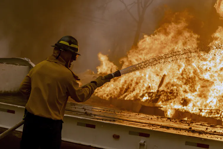 A firefighter sprays water from a house at a fire