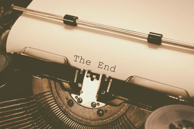 Uma velha máquina de datilografar com uma folha de papel onde se lê as palavras "The End" (fim)