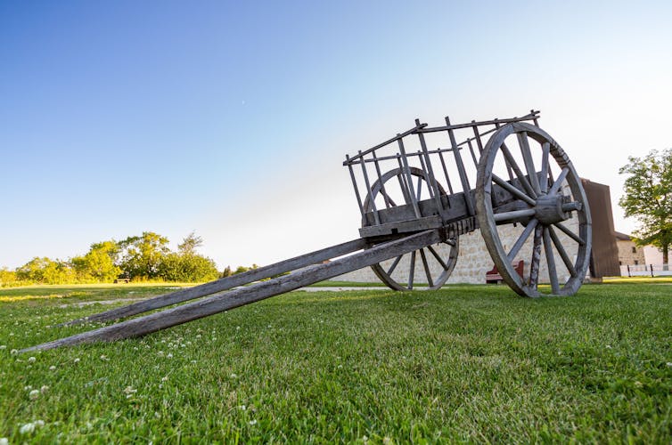 A two-wheeled open wooden cart in a field