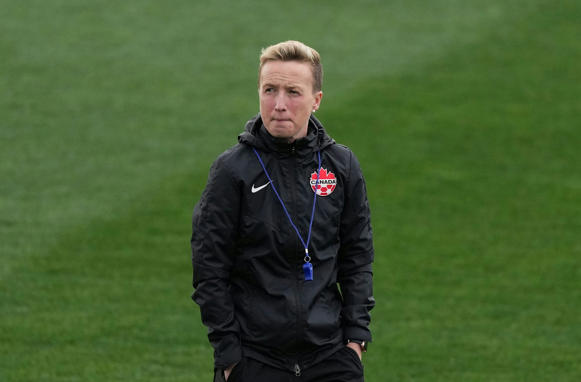 A women in a black tracksuit walking on a pitch