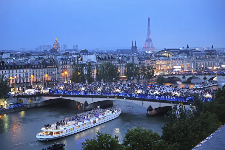 A river boat passes under a bridge.