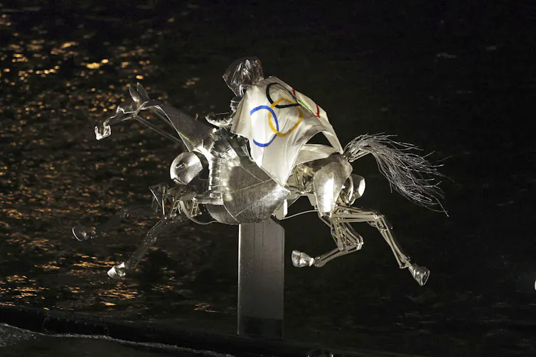 The Horsewoman, draped in the Olympic flag, rides along on the River Seine.
