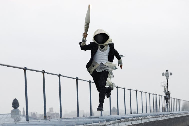 A torch bearer runs atop the Musee d'Orsay,