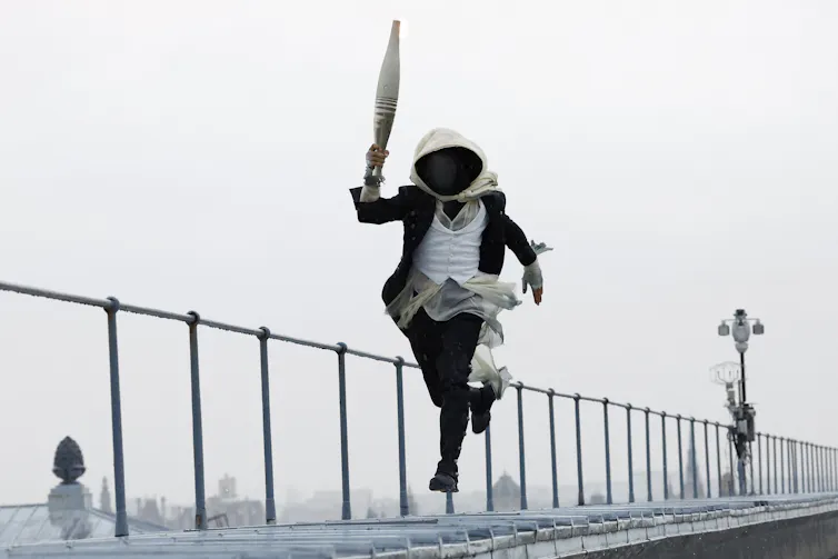 A torch bearer runs atop the Musee d'Orsay,