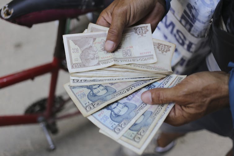 Close up of a fan of Cuban pesos seen in someone's hands