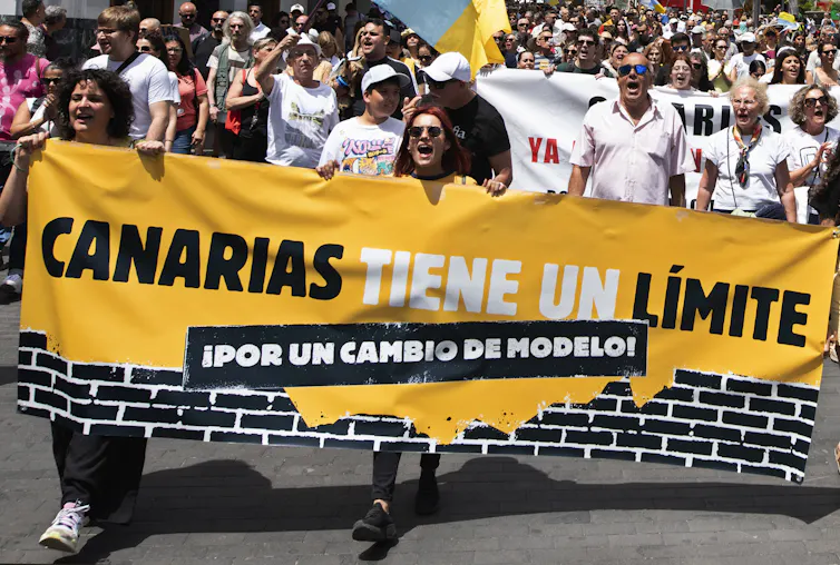 People at a demonstration carry a large banner reading: 'Canary Islands have limits, for a change of model.'