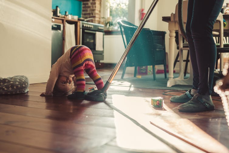toddler bent over, parent from the waist down, vacuuming