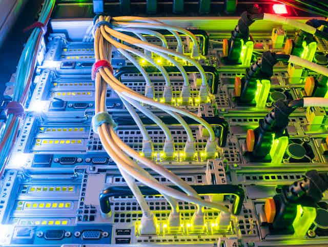 Close-up of yellow and blue lit rows of cables at a large computer.