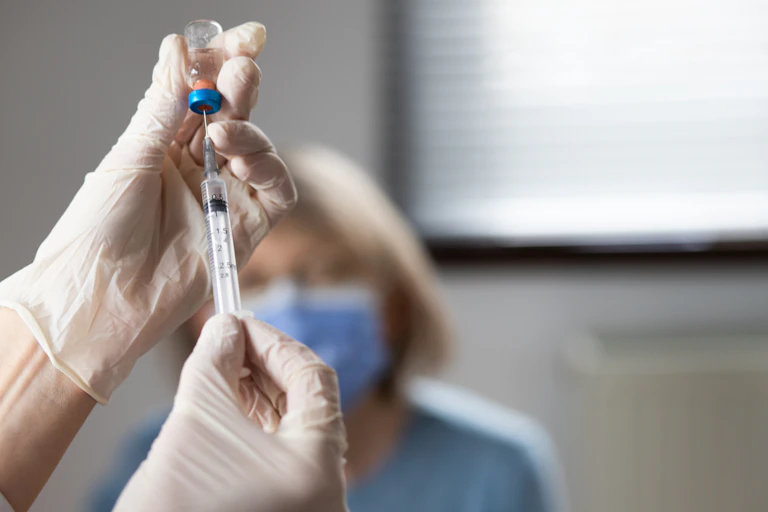 Gloved hands drawing up a vaccination.