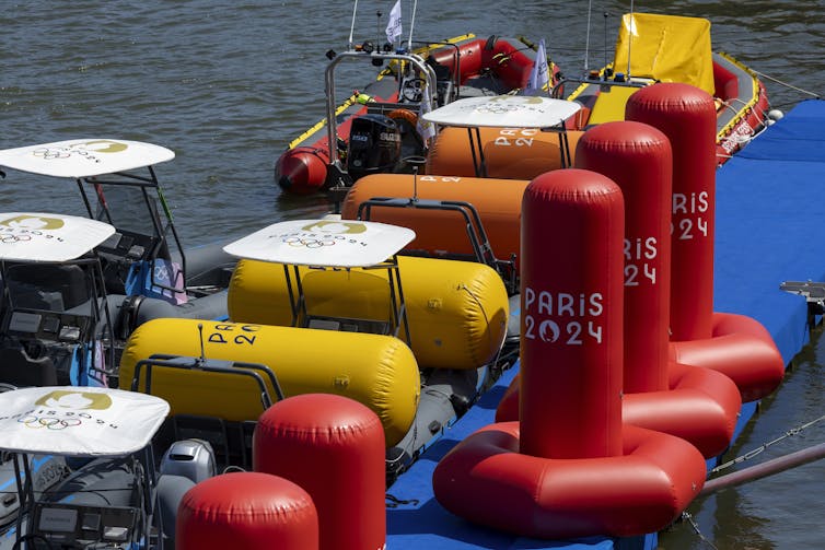 Colourful buoys and boats moored at the side of a river.