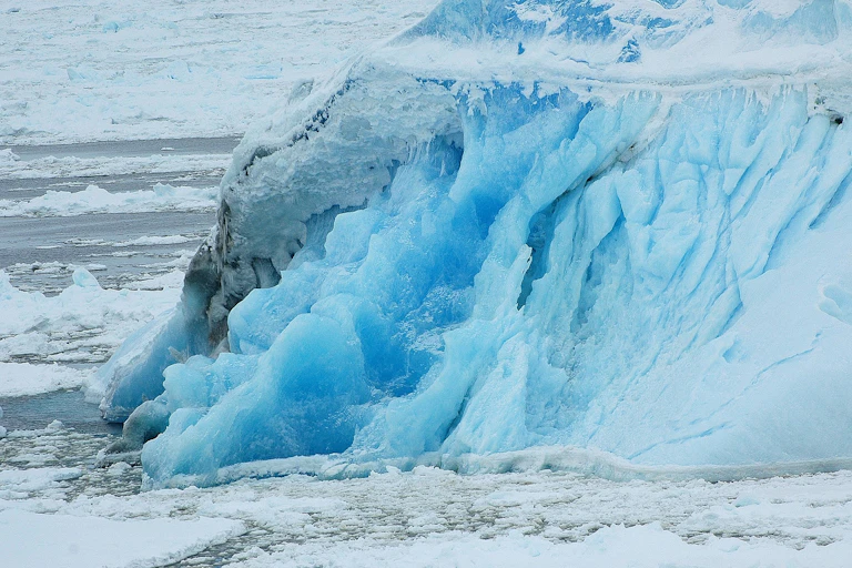 A large mass of sea ice visibly melting into the sea