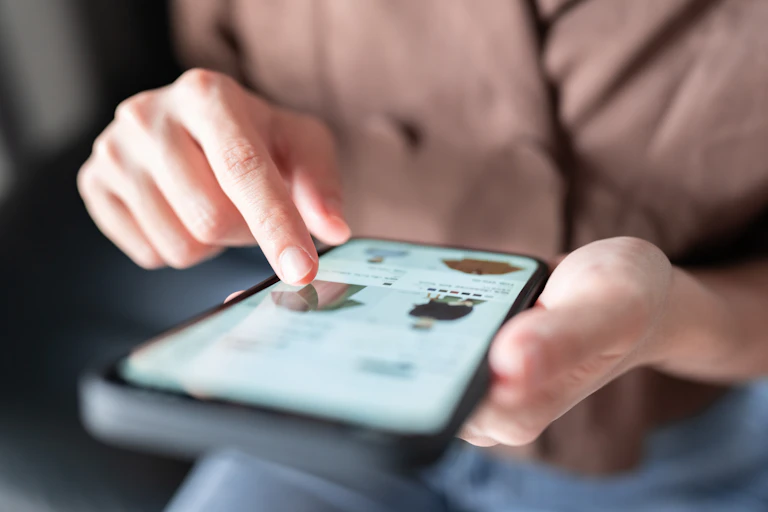 A woman is seen shopping for clothes on a smartphone.