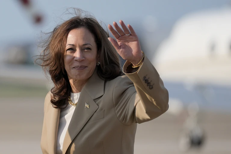 Kamala Harris debout devant un avion, saluant de la main gauche