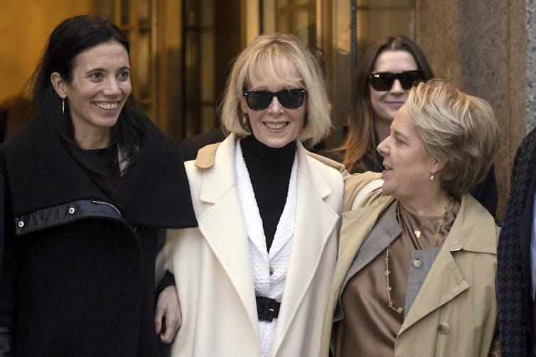 A woman in white seen surrounded by people smiling.