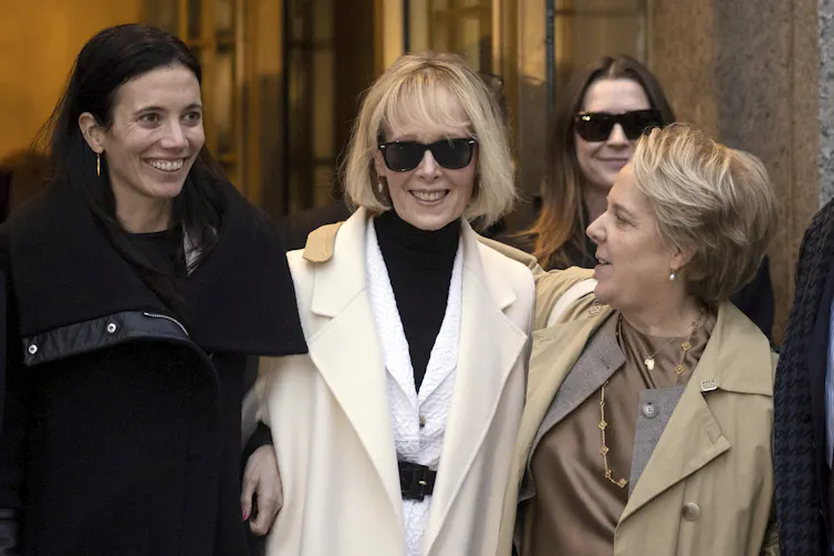 A woman in white seen surrounded by people smiling.