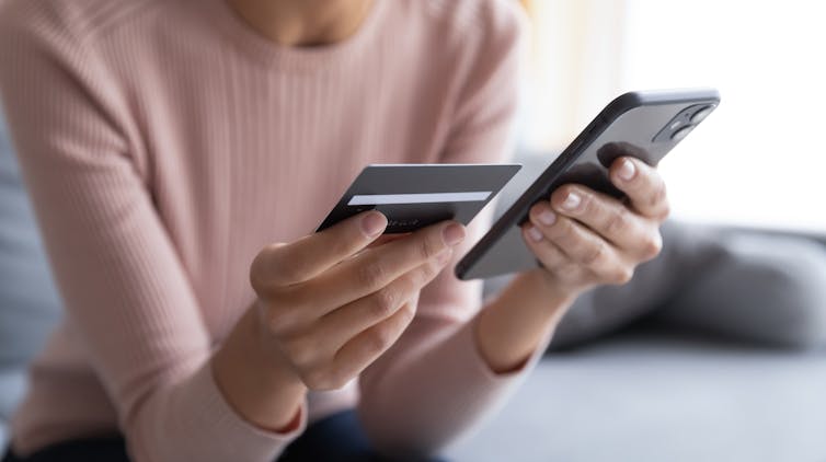 Closeup of hands holding phone and a credit card