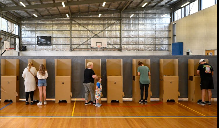 People stand at voting booths in a gymnasium