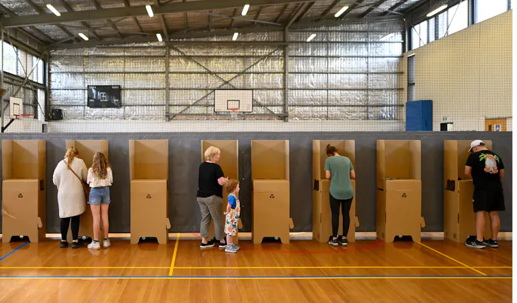 People stand at voting booths in a gymnasium