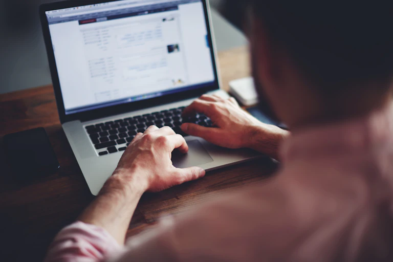 A man sitting at a desk, types on a laptop
