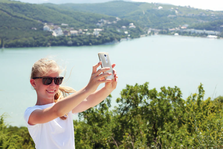 A girl takes a selfie overlooking water.