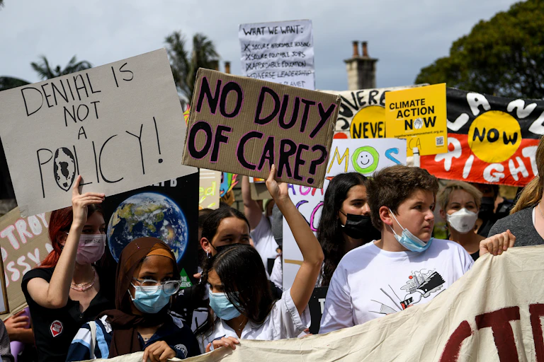 A group of young people protesting outside holding signs