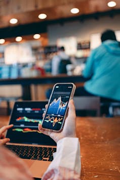 Hands of a woman using smartphone looking at cryptocurrency graph