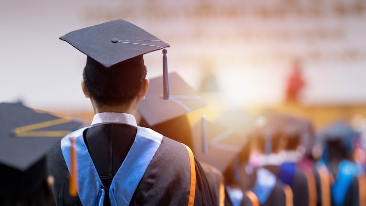 University graduate seen facing away from camera at a graduation ceremony