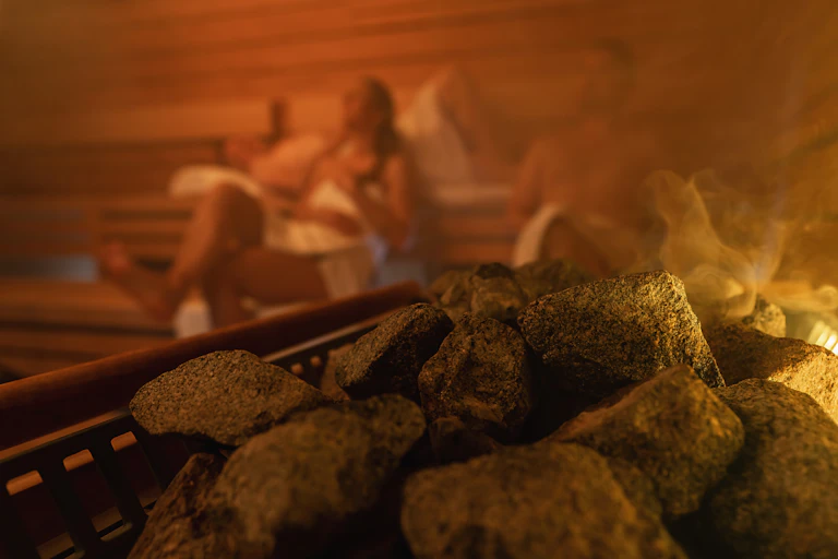 Des personnes dans un sauna, avec des pierres chaudes en premier plan