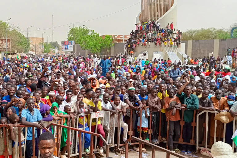 Crowd of people outdoors, up against metal barriers
