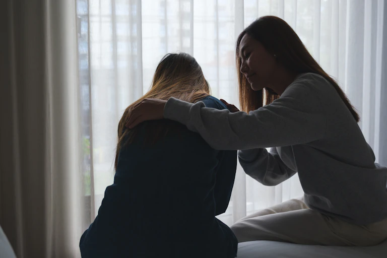 View in shadow of a woman comforting her friend