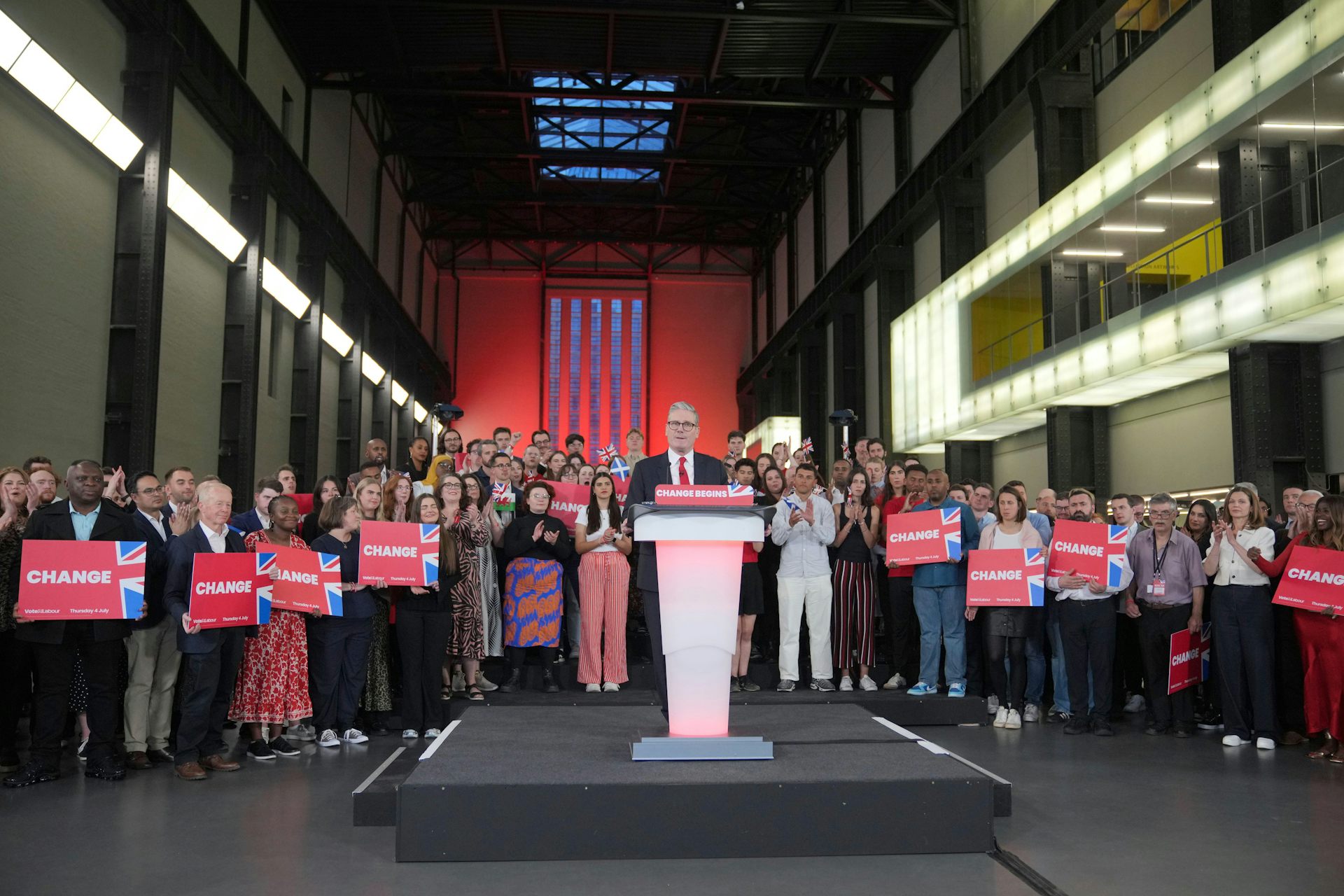 Labour leader Keir Starmer standing with supporters in a large gallery space.