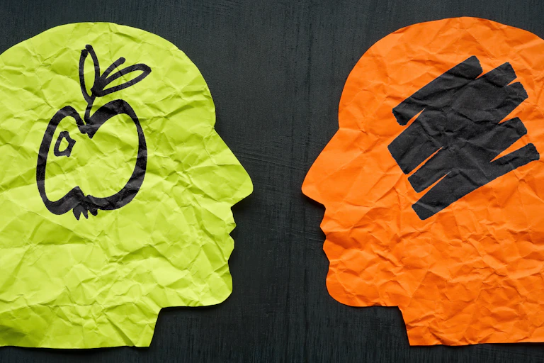 Outlines of two human heads. In one of the heads is a drawing of an apple, in the other is scribble.