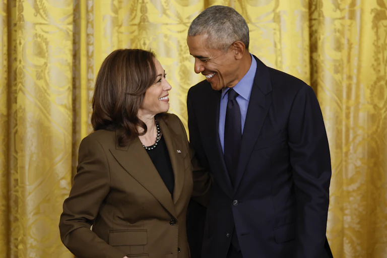 A brown-haired woman and a gray haired man smile broadly at each other.