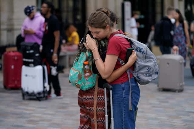 People hug outside train station.
