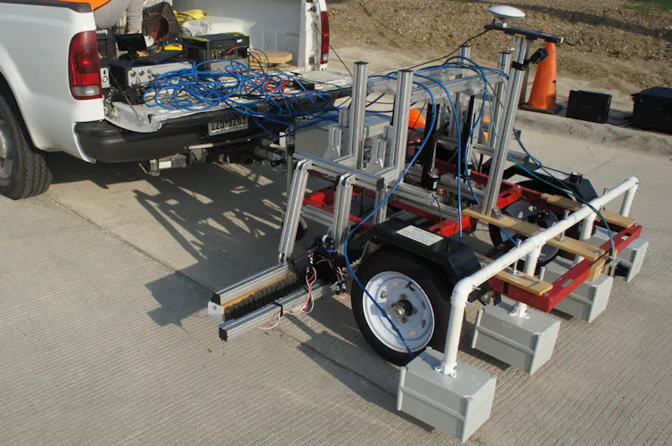 A truck with a row of four scanning devices spaced out behind. Each is about the size of a cinder block.