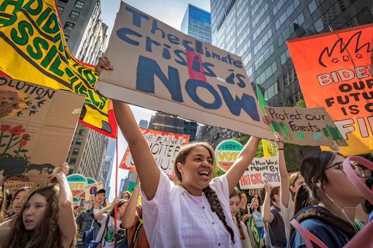 Activists hold signs, including: The climate crisis now