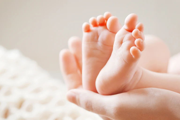 A baby's feet resting in an unidentified woman's hand
