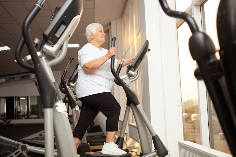 An older woman works out on a machine at the gym.