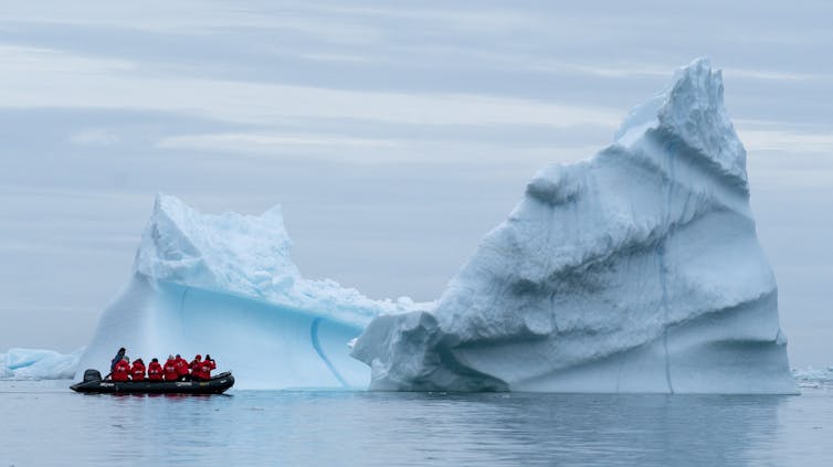 boat sails up to iceberg