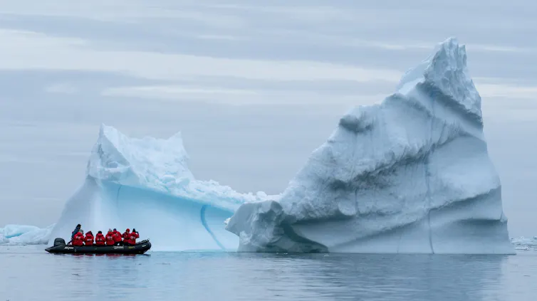 boat sails up to iceberg