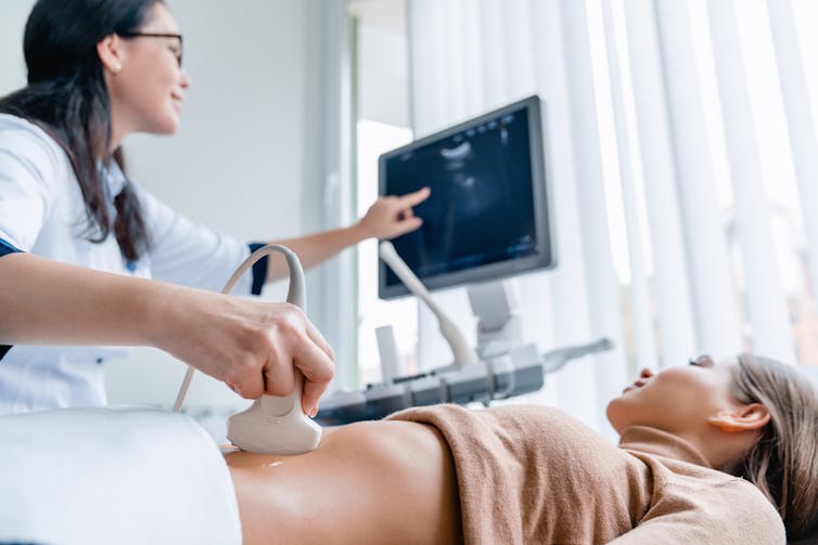 health worker ultrasounds a woman's belly in a clinical setting