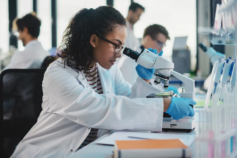 male and female scientists working in lab at microscopes