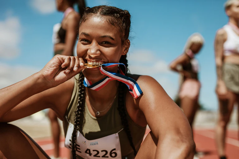 Female athlete biting gold medal