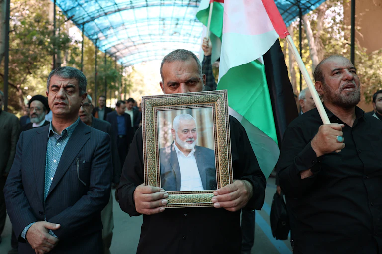Des hommes portent le portrait d'Ismaïl Haniyeh et un drapeau palestinien