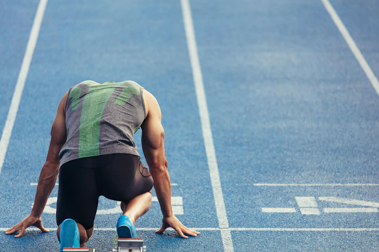 Rear view of a sprinter at a starting block.