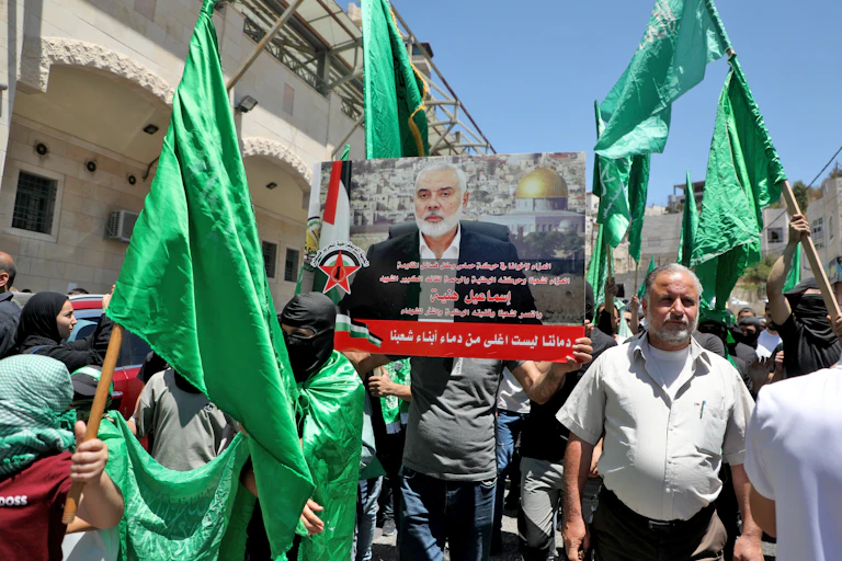Men holding green flags hold aloft a photo of a man in a suit with a beard.