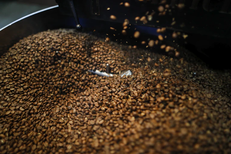Uma grande pilha de grãos de café em uma caixa de metal.