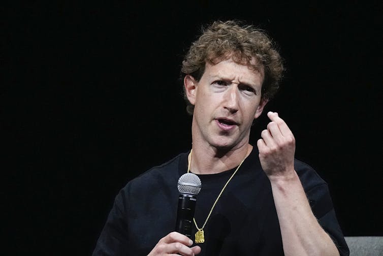 Man holding microphone talking on stage.